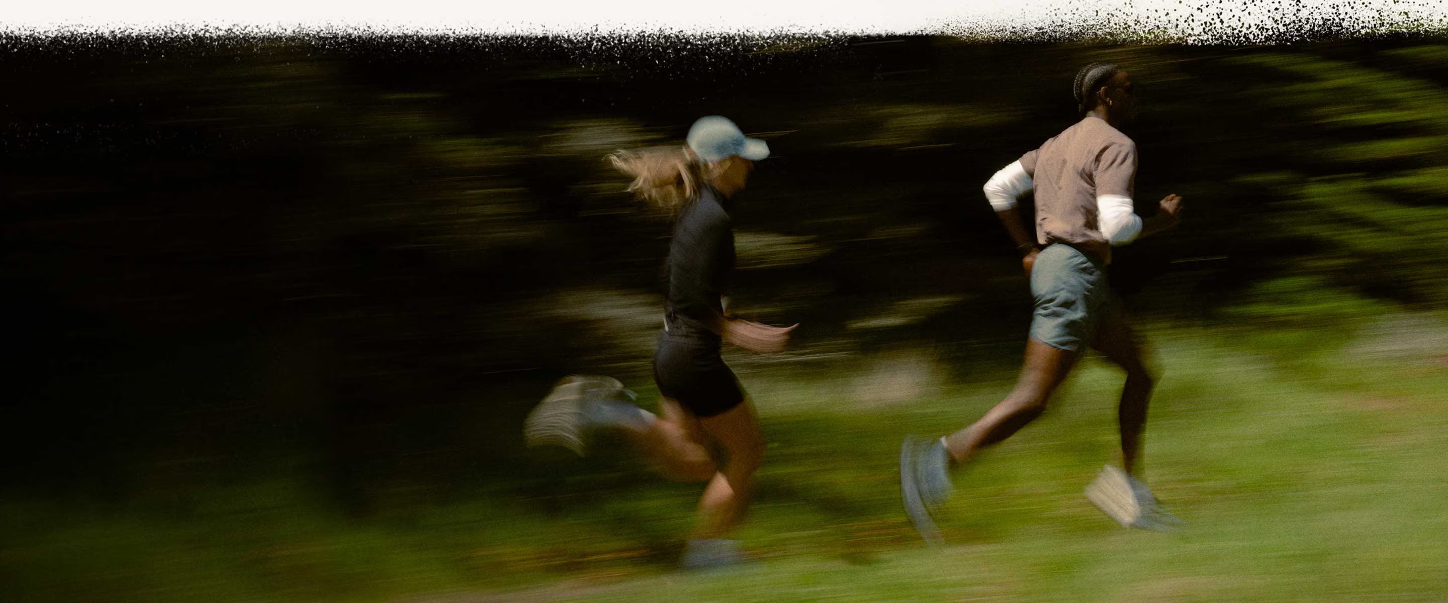 Two people running across a green field