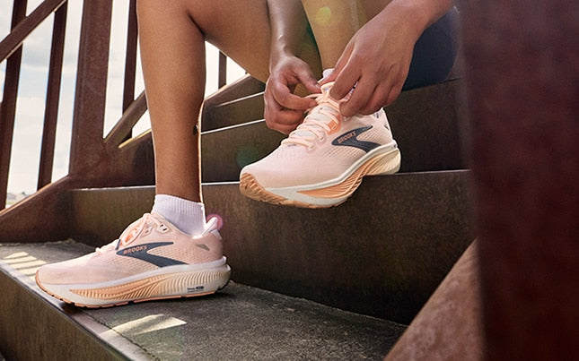 Runner tying a Brooks Ghost shoe on concrete stairs